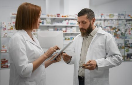 female-pharmacist-training-male-coworker-with-tablet-pharmacy